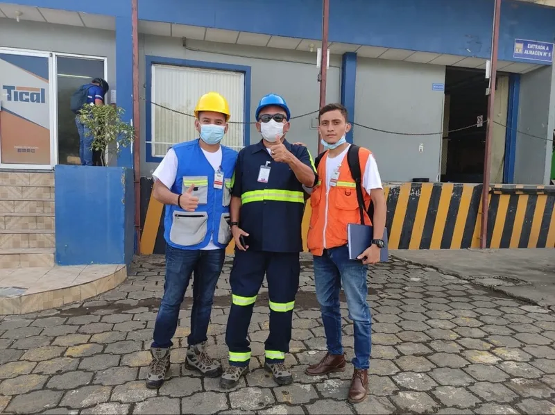 Tres personas con equipo de protección frente al acceso a un almacén industrial de un cliente.